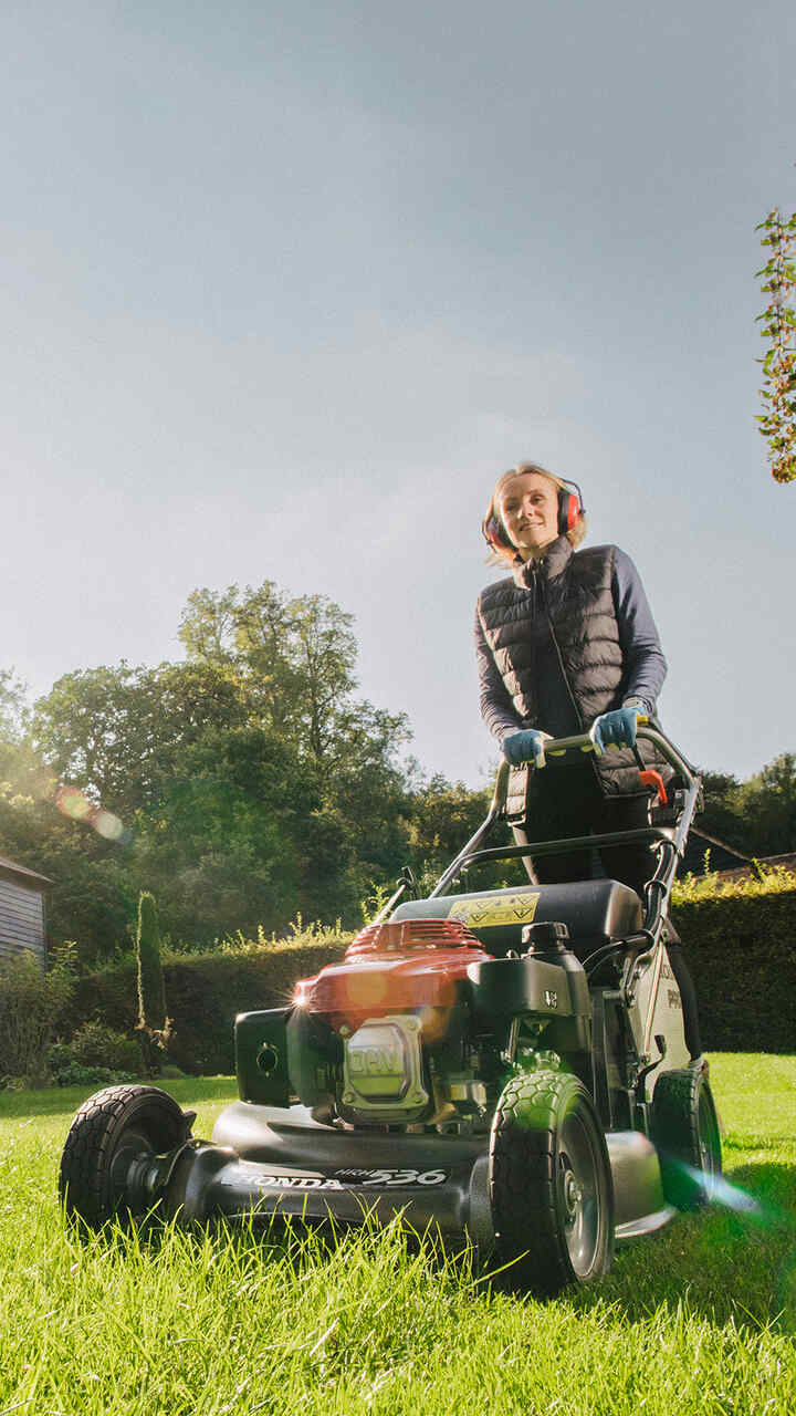 Mann beim Schieben eines HRH-Rasenmähers im Garten.