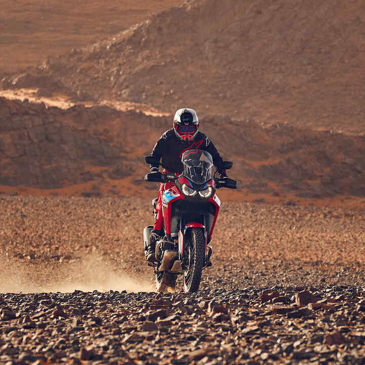 Fahrer auf einer CRF1100 Africa Twin Adventure Sports im Gelände, 3/4-Frontansicht.